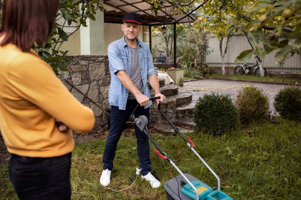 Man trimming grass with a lawn mower in a garden setting.